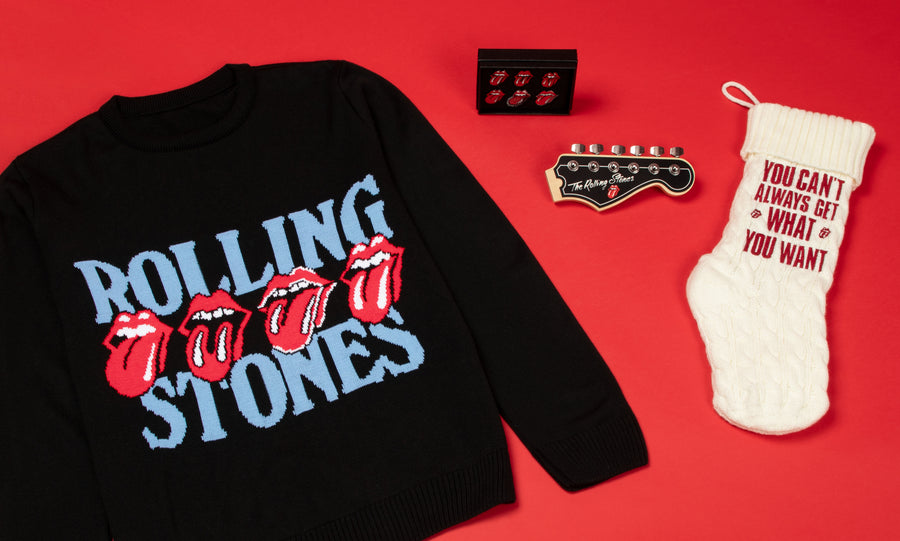Rolling stones sweater, stocking, and enamel pins on a red background